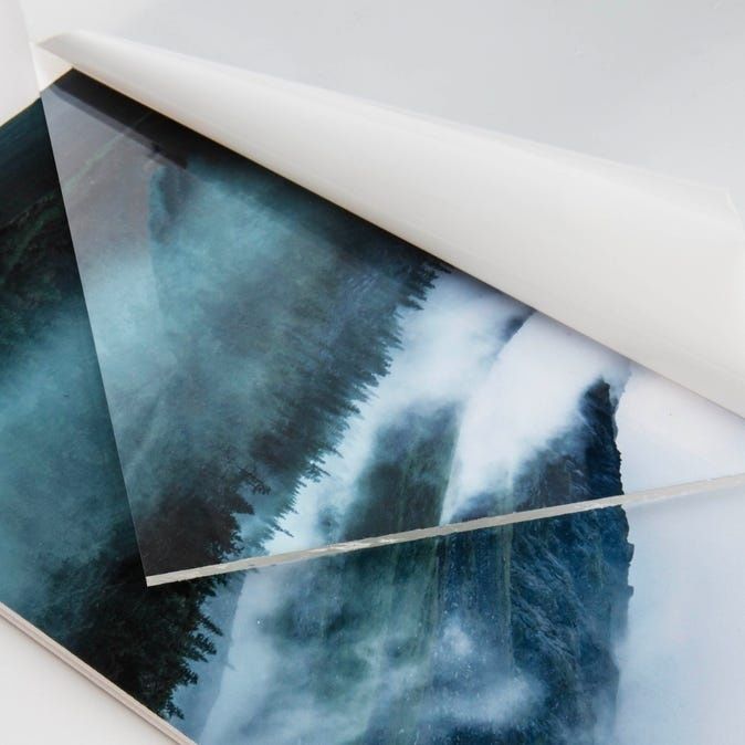 Nahaufnahme eines gerahmten Wasserfallbildes unter glänzendem Schutzglas